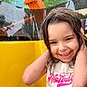 child, smiling, wet_hair, yellow, orange, outdoor, playground, raindrops, happy, person, tshirt, nature, trees, building, portrait, young, cute, fun, colorful, daylight