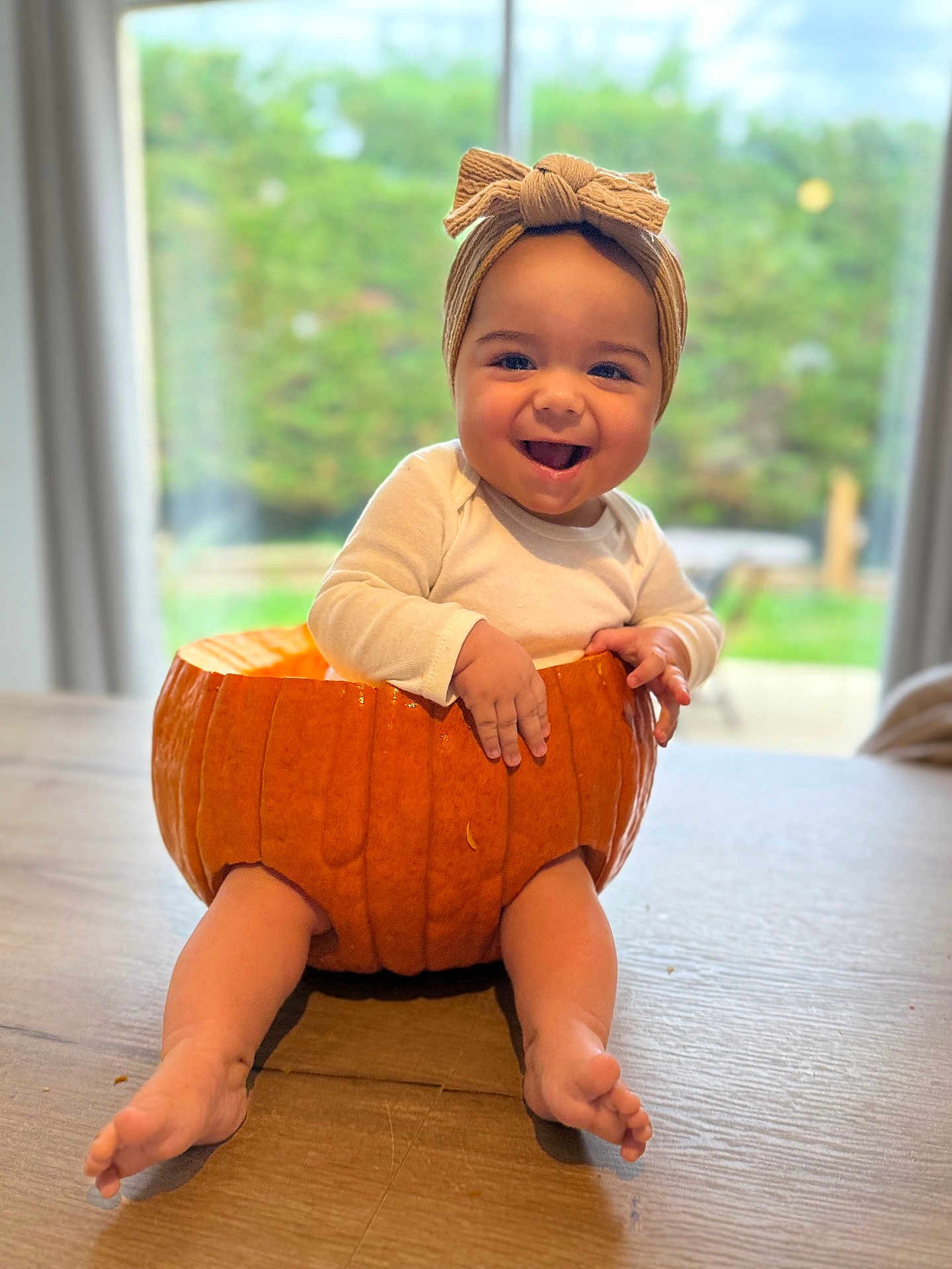 Malya participe au concours pour gagner de l'argent avec cette photo : baby, pumpkin, headband, smile, happy, table, indoor, child, cute, orange, festive, holiday, costume, autumn, window, natural_light, portrait, sitting, hands, feet