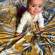 Malya a rejoint le concours — aidez-le/la à gagner de superbes lots ! baby, child, infant, crawling, smiling, face, bedspread, pattern, yellow, gray, clothing, long_sleeve, indoors, floor, person, cute, happy, portrait, young, home