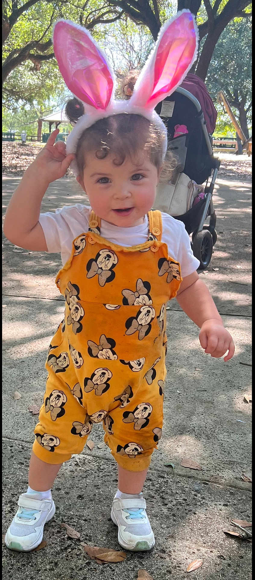Genesis Hernandez is registered to the contest to win money with this photo: toddler, child, bunny_ears, yellow_overall, white_shirt, sneakers, outdoor, park, stroller, trees, sunlight, sidewalk, playful, happy, curly_hair, person, nature, daylight, cute, smiling