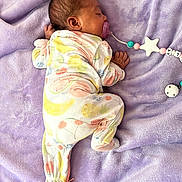 Lola is registered to the contest to win money with this photo: baby, blanket, child, clothing, cute, face, fruit_pattern, hand, head, indoors, infant, lying_down, newborn, onesie, pacifier, peaceful, purple, resting, sleeping, soft_texture