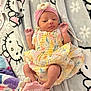 baby, blanket, child, colorful_dress, cozy, cute, fabric, footwear, hands_up, hello_kitty, indoors, infant, lying_down, newborn, pastel_colors, pattern, pink_headband, sleepwear, socks, soft_texture