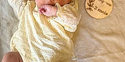 Lily-Rose a rejoint le concours — aidez-le/la à gagner de superbes lots ! baby, infant, child, lying_down, blanket, soft_texture, clothing, hand, face, eyes, foot, plaque, wooden, age_marker, cute, curious, indoors, portrait, newborn, skin