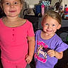 child, children, smiling, indoors, carpet, dresser, clothing, pink_outfit, purple_outfit, holding_hands, person, happy, footwear, toy, room, mirror, fan, bottle, casual, portrait