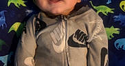 Malakai joined the competition — help win amazing prizes! baby, casual, child, clothing, colorful, comfort, cute, dinosaur_pillow, face, happy, indoors, infant, lying_down, nike, onesie, playful, portrait, smiling, soft_lighting, young_child