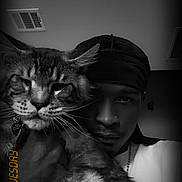 Simon is registered to the contest to win money with this photo: cat, person, portrait, black_and_white, indoor, fluffy, long_hair, pet, human, close_up, selfie, whiskers, eyes, nose, headwear, chain, dramatic_lighting, date_stamp, home, cuddling