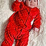 baby, infant, red_clothing, santa_hat, festive, christmas, soft_texture, fur_rug, sleepwear, cute, smiling, portrait, lying_down, holiday, child, one_person, indoors, cozy, warm, celebration