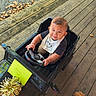 autumn, baby, bib, child, clothing, face, happy, leaves, mercedes, outdoor, photography, portrait, ride_on_car, sitting, smiling, steering_wheel, toddler, toy_car, vehicle, wooden_deck