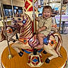 Sincere joined the competition — help win amazing prizes! amusement_ride, baby, beige_outfit, carousel, carousel_horse, child, clothing, colorful, entertainment, family_activity, happy, horse, indoor, infant, playground, portrait, riding, shopping_mall, sitting, smiling