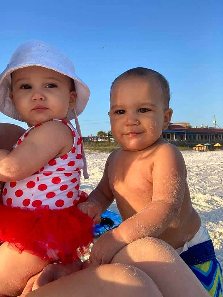 Kamari is registered to the contest to win money with this photo: baby_toddler_clothing, eye, face, facial_expression, finger, happy, head, headwear, joy, leg, light, muscle, organ, people_on_beach, person, photograph, skin, sky, summer, swimwear