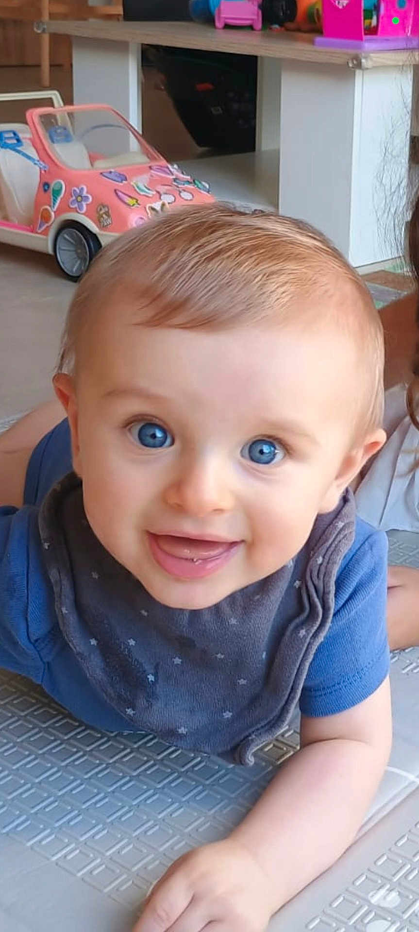 Nathan participe au concours pour gagner de l'argent avec cette photo : baby, blue_eyes, smiling, crawling, bib, blue_shirt, indoor, toy_car, floor_mat, child, playful, cute, face, expression, young_child, hair, person, happy, closeup, furniture