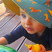 Nathan a rejoint le concours — aidez-le/la à gagner de superbes lots ! toddler, child, blue_eyes, hat, sun_hat, animal_print, rubber_duck, inflatable_pool_toy, green, wooden_deck, outdoor, summer, play, toy, cute, close_up, person, baby, sunlight, curious