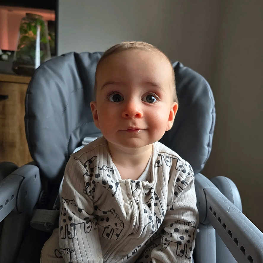 Louis participe au concours pour gagner de l'argent avec cette photo : baby, child, clothing, curious, drool, expression, eyes, face, furniture, giraffe_print, hands, high_chair, indoor, infant, neutral_background, onesie, portrait, seat, soft_lighting, stain