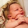 Maisie is registered to the contest to win money with this photo: baby, infant, headband, bow, pearls, hand, skin, face, expression, tongue, soft_fabric, blanket, closeup, cute, newborn, lying_down, portrait, child, playful, indoors