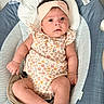 baby, infant, child, portrait, face, wide_eyes, headband, floral_outfit, sitting, baby_seat, cushion, striped_fabric, plush_toy, stuffed_animal, indoor, close_up, adorable, alert, family_photo, safe
