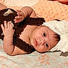 Zoe is registered to the contest to win money with this photo: baby, infant, child, portrait, lying_down, blanket, bed, headband, white_clothing, dark_clothing, frills, face, eyes, smiling, indoor, close_up, cute, newborn, patterned_fabric, photography