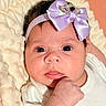 baby, infant, child, portrait, close_up, face, eyes, bow, headband, blanket, onesie, hand, fist, lying_down, indoors, cozy, lavender, white_clothing, photography, cute