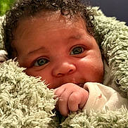 Aria-Leigh joined the competition — help win amazing prizes! baby, infant, face, hand, blanket, curly_hair, green_blanket, close_up, cute, child, soft_texture, warm, portrait, skin, eyes, cozy, newborn, expression, wrapped, toddler