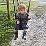 Solan a rejoint le concours — aidez-le/la à gagner de superbes lots ! toddler, child, swing, rain_boots, gray_sweater, park, grass, gravel_path, outdoor, daylight, playground, young_child, person, tree, bench, casual_clothing, nature, fun, cute, happy