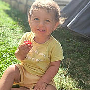 Solan participe au concours pour gagner de l'argent avec cette photo : child, toddler, smiling, grass, outdoor, sunlight, yellow_clothing, berry, happy, sitting, nature, baby, casual, cute, portrait, daylight, face, hands, grass_field, playful