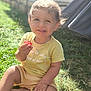 child, toddler, smiling, grass, outdoor, sunlight, yellow_clothing, berry, happy, sitting, nature, baby, casual, cute, portrait, daylight, face, hands, grass_field, playful