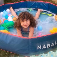 Djodie a rejoint le concours — aidez-le/la à gagner de superbes lots ! child, curly_hair, pool, inflatable_pool, bubbles, plastic_balls, outdoor, grass, play, smile, toy, summer, water, fun, young, happy, splash, recreation, sunlight, relaxation