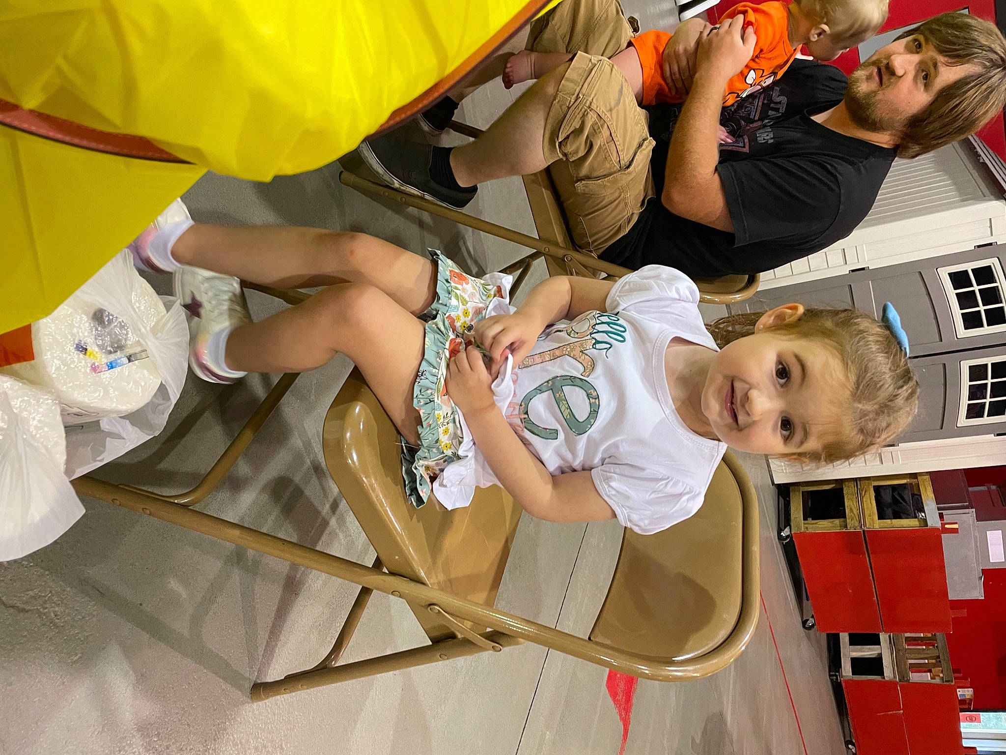 Caroline is registered to the contest to win money with this photo: arm, baby, chair, child, event, fun, happy, human_leg, leisure, motor_vehicle, person, play, recreation, sandal, shorts, smile, sneakers, t_shirt, thigh, toddler