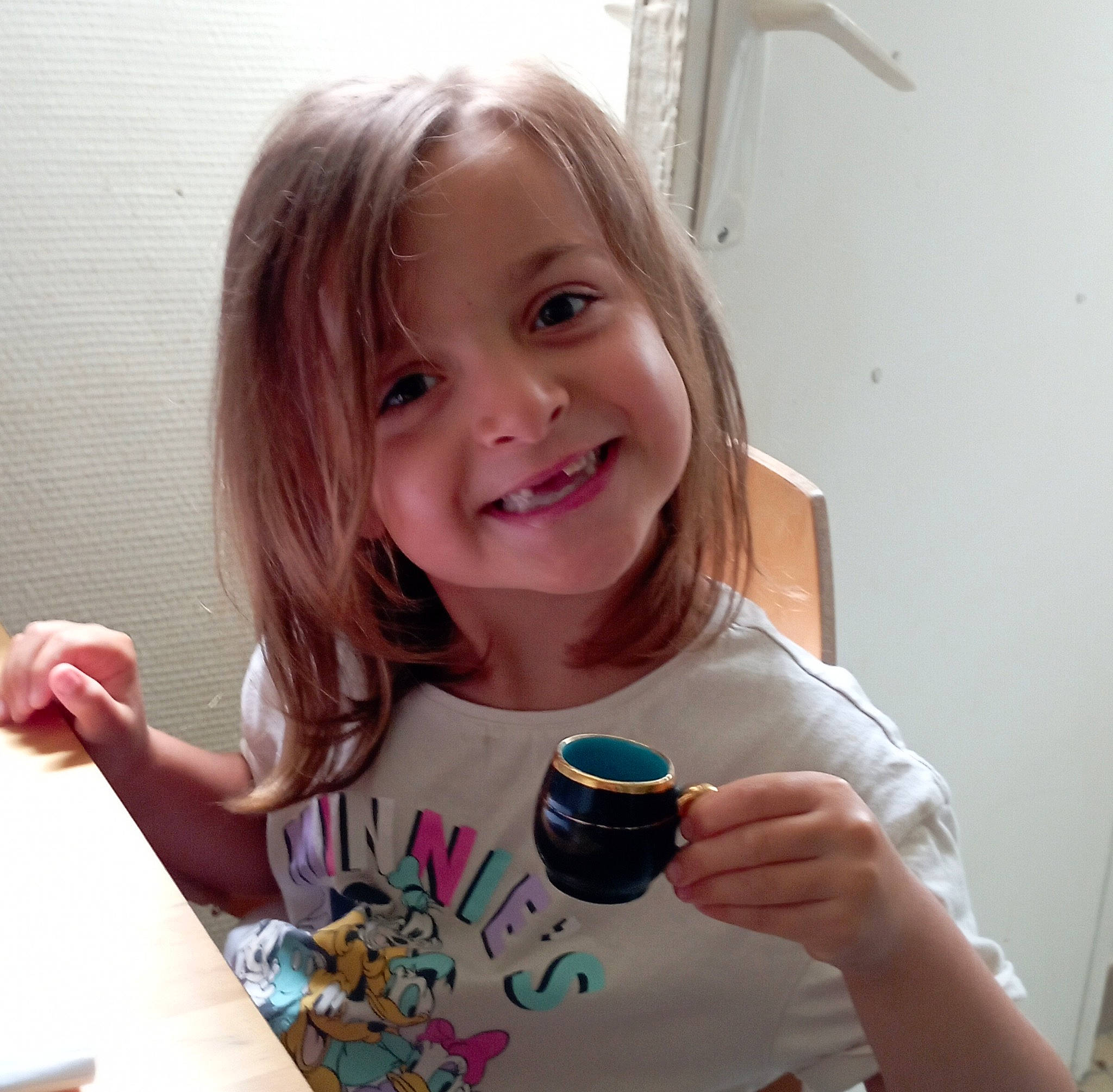 Eva participe au concours pour gagner de l'argent avec cette photo : brown_hair, cheek, child, drinkware, eyelash, facial_expression, finger, fun, gesture, hair, hand, happy, iris, joy, nail, person, smile, sweetness, t_shirt, tableware