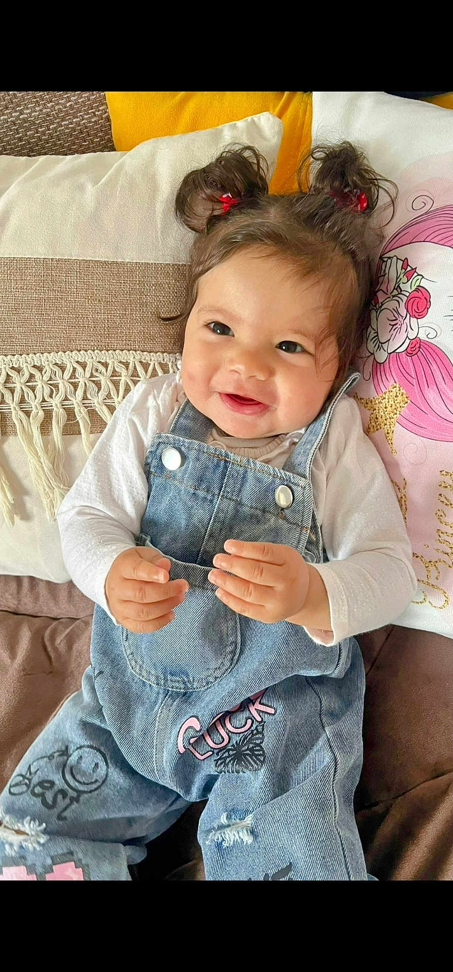 Ghazal participe au concours pour gagner de l'argent avec cette photo : baby, child, smiling, denim_overalls, pigtails, red_hair_ties, couch, pillow, cozy, indoor, cute, happy, portrait, toddler, clothing, hands, face, hair, seated, comfortable