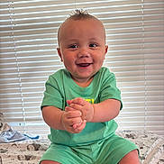 Savion joined the competition — help win amazing prizes! baby, blanket, child, clapping, cute, expression, face, green_clothing, hands, happy, indoor, infant, light, natural_light, patterned_blanket, portrait, sitting, smiling, toddler, window_blinds