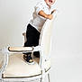 toddler, child, smiling, standing, white_chair, white_background, black_pants, white_shirt, sneakers, nike, happy, portrait, studio_photo, furniture, young_child, indoors, person, cute, fashion, playful