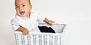 Liam joined the competition — help win amazing prizes! toddler, child, white_shirt, wicker_basket, smiling, happy, studio, minimalistic, portrait, baby, sitting, cute, indoor, person, face, head, photography, clothing, hands, expression