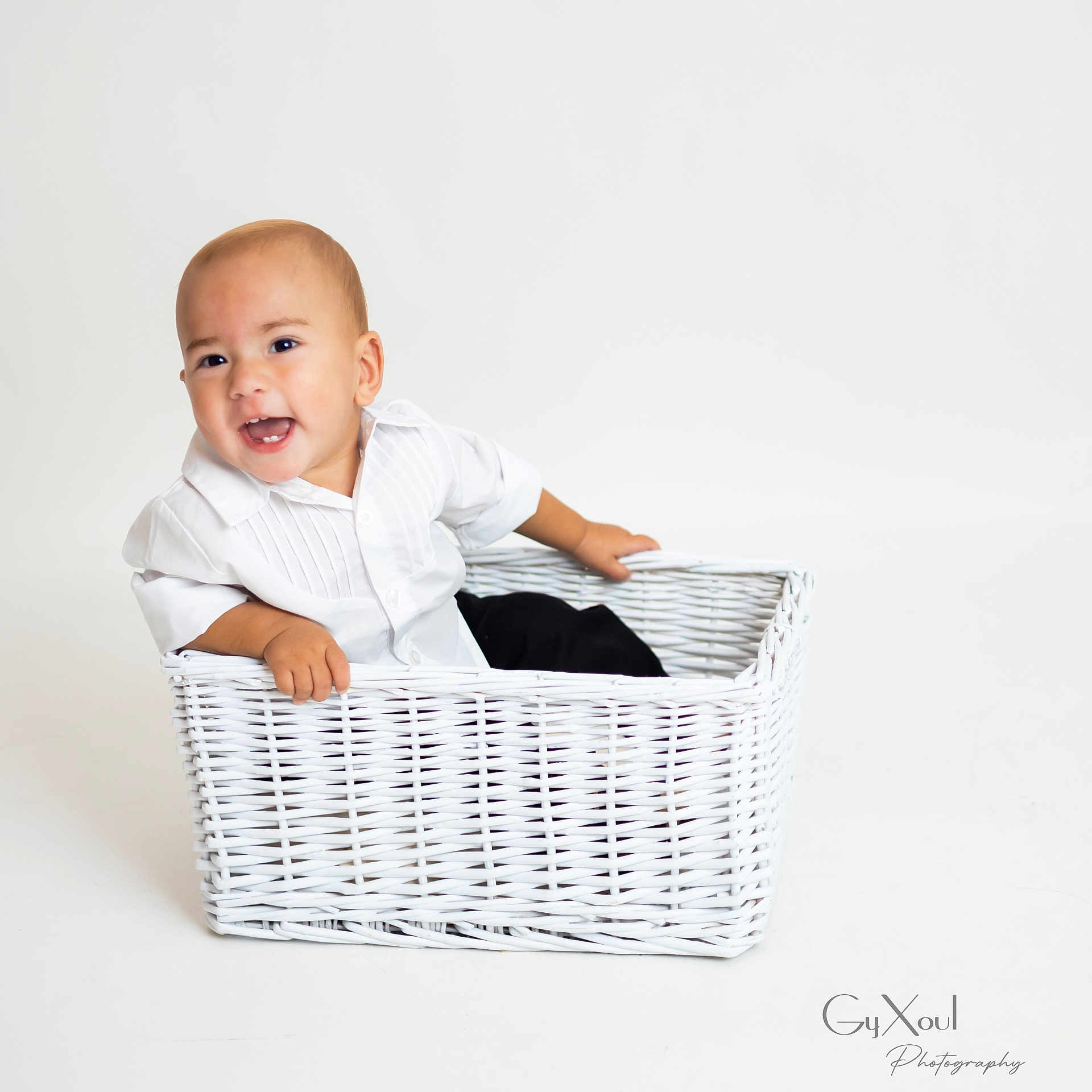 Liam joined the competition — help win amazing prizes! toddler, child, white_shirt, wicker_basket, smiling, happy, studio, minimalistic, portrait, baby, sitting, cute, indoor, person, face, head, photography, clothing, hands, expression