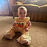 baby, child, carpet, yellow_outfit, indoor, couch, dog, pet, furniture, carrot_design, cute, portrait, sitting, face, person, home, cozy, carpeted_floor, animal, living_room