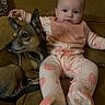 baby, infant, dog, couch, pajamas, butterfly_pattern, pet, animal, child, indoor, furniture, relaxing, cute, young_child, portrait, companionship, cozy, casual, home, seated