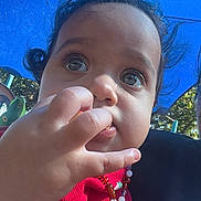 Leearnah joined the competition — help win amazing prizes! child, baby, toddler, face, portrait, outdoor, sunlight, blue_background, red_clothing, curly_hair, brown_hair, large_eyes, curious, hand, finger, necklace, jewelry, seated, close_up, candid