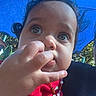 child, baby, toddler, face, portrait, outdoor, sunlight, blue_background, red_clothing, curly_hair, brown_hair, large_eyes, curious, hand, finger, necklace, jewelry, seated, close_up, candid