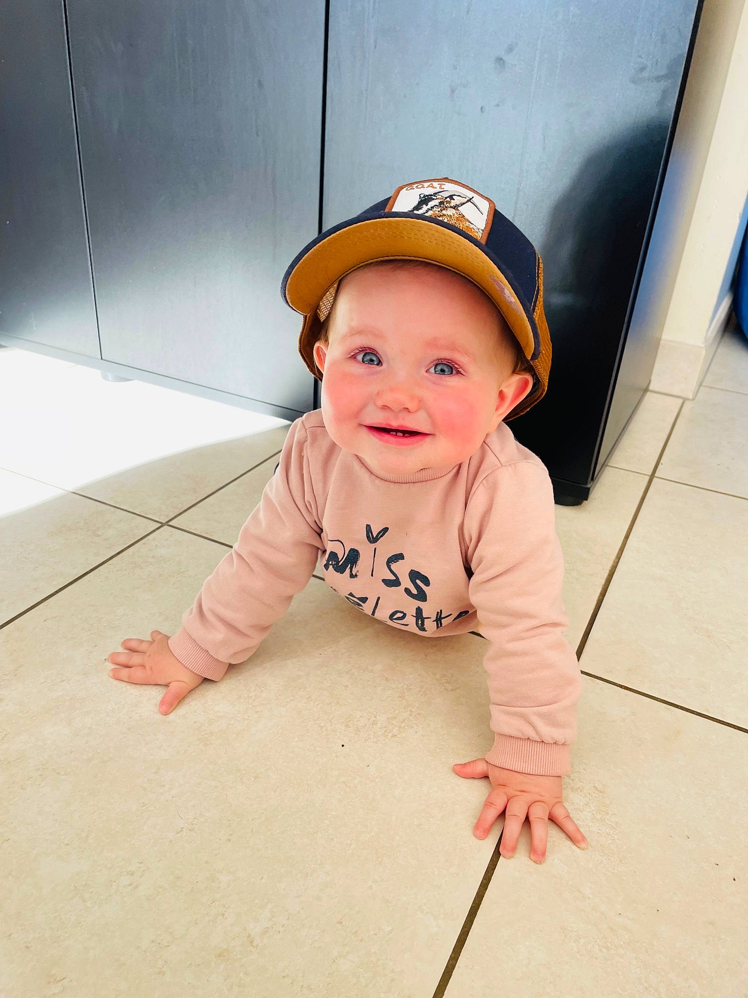 Ambre a rejoint le concours — aidez-le/la à gagner de superbes lots ! baby, baby_toddler_clothing, baseball_cap, cap, child, face, fashion_accessory, floor, flooring, fun, happy, hardwood, hat, headwear, joy, pattern, person, portrait_photography, sleeve, smile