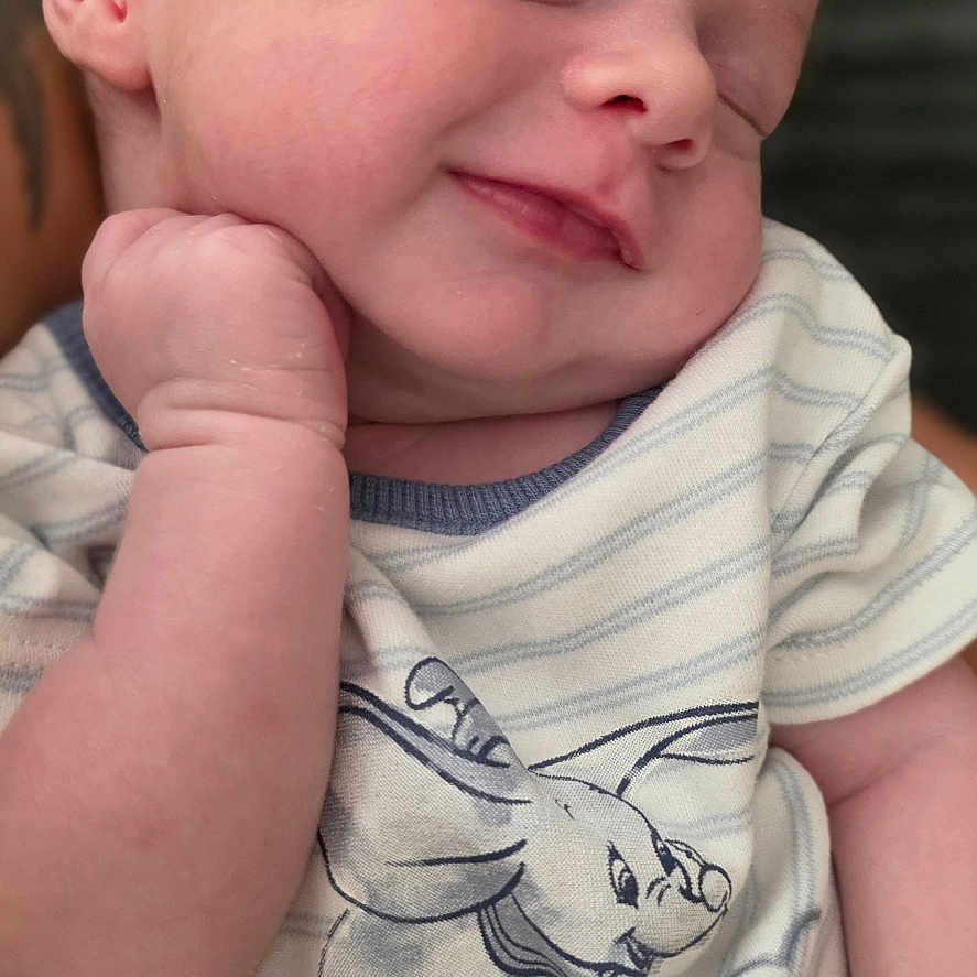 Noah is registered to the contest to win money with this photo: baby, child, closeup, clothing, cute, elephant_print, face, hand, infant, newborn, peaceful, person, portrait, resting, skin, sleeping, smiling, soft_light, striped_shirt, toddler