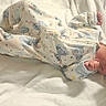 newborn, baby, infant, sleeping, lying_down, bed, blanket, white_bedding, pajamas, clothing, bow, headband, face, hands, feet, indoors, portrait, soft_lighting, nursery, family_photo