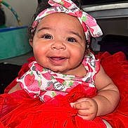 Ocean is registered to the contest to win money with this photo: baby, child, smiling, headband, red_dress, tutu, indoor, cute, happy, infant, clothing, person, portrait, sitting, closeup, hand, curly_hair, face, baby_girl, expression