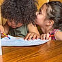 child, children, coloring, crayons, worksheet, table, wooden_table, curly_hair, long_hair, whispering, intense, focus, playful, indoor, seated, clothing, sleeveless_shirt, smiling, friendship, cute