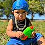 Jahmarii joined the competition — help win amazing prizes! toddler, child, outdoor, grass, blue_headwrap, gold_chain, water_gun, summer, sunlight, casual_clothing, portrait, baby, serious_expression, toy, nature, greenery, sitting, playful, daytime, young_child