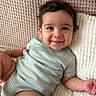 baby, child, infant, smiling, happy, portrait, indoors, lying_down, blanket, pillow, knit_texture, onesie, green_clothing, brown_hair, face, eyes, arms, legs, cozy, home
