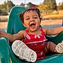 toddler, child, swing, playground, smiling, happy, outdoor, red_dress, green_swing, summer, joy, cute, baby, feet, shoes, sunlight, park, fun, blurred_background, nature