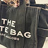 kitten, cat, tote_bag, black_bag, canvas_bag, pet, cute, animal, feline, small, paw, curious, indoor, playful, closeup, text, fabric, handle, white_text, Marc_Jacobs