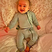 Kannon is registered to the contest to win money with this photo: baby, child, infant, smiling, laughing, sitting, bed, bedding, onesie, clothing, portrait, indoors, bedroom, blanket, pillow, leopard_pattern, happy, social_media, screenshot, baby_photo