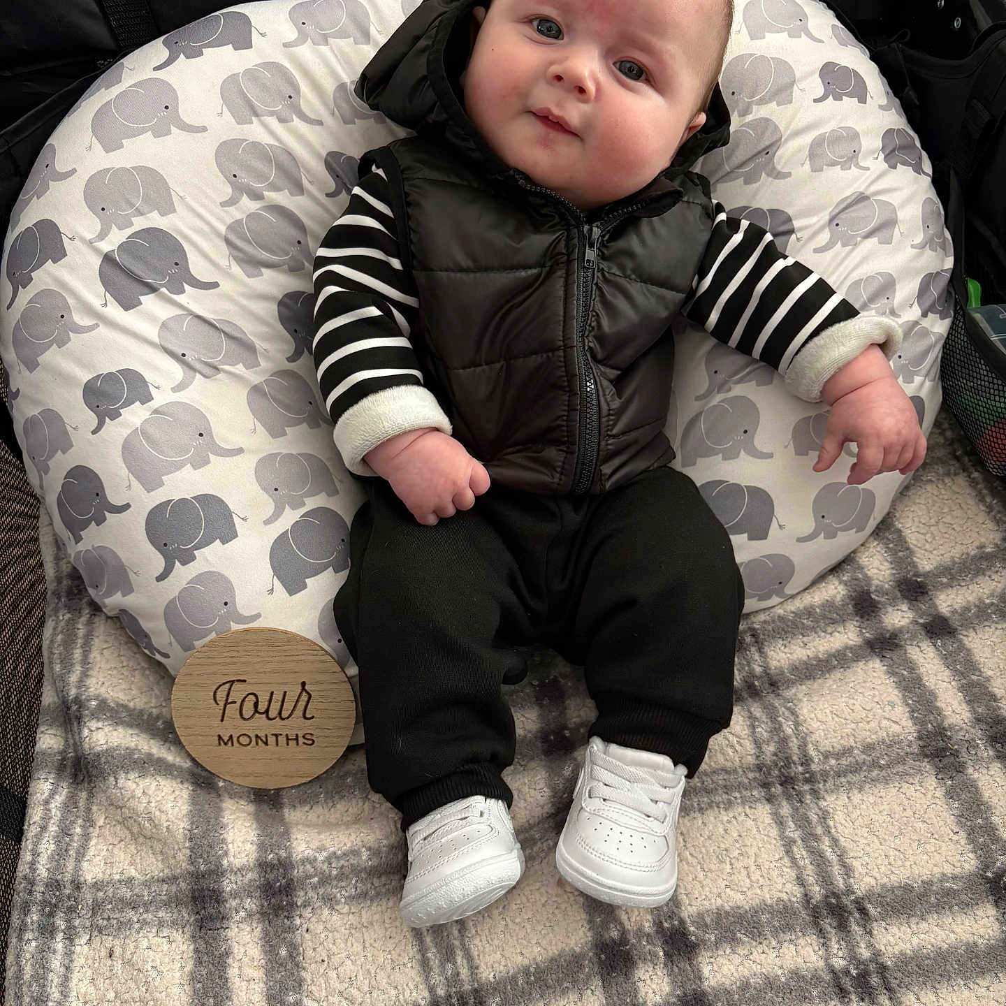 Camilo is registered to the contest to win money with this photo: baby, black_vest, blanket, child, clothing, cozy, cute, elephant_pattern, face, four_months, indoors, infant, pillow, plaid, portrait, seated, soft, striped_shirt, white_sneakers, young_child