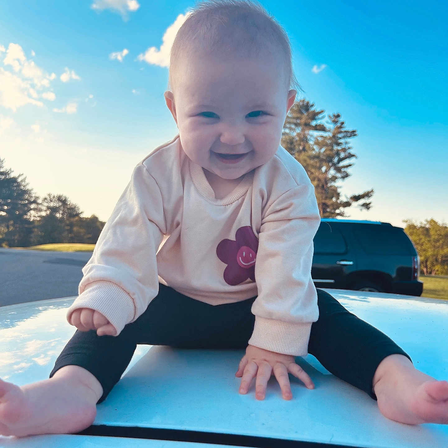 Cecilia joined the competition — help win amazing prizes! baby, barefoot, blue_sky, car, casual_clothing, child, clouds, cute, flower_design, grass, happy, hood, nature, outdoor, person, playful, smiling, sunlight, sweater, trees