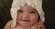 Everly is registered to the contest to win money with this photo: baby, child, smiling, diaper, headwear, peach_outfit, floral_print, cute, infant, portrait, happy, sitting, indoors, soft_lighting, clothing, face, chubby_cheeks, funny, playful, person